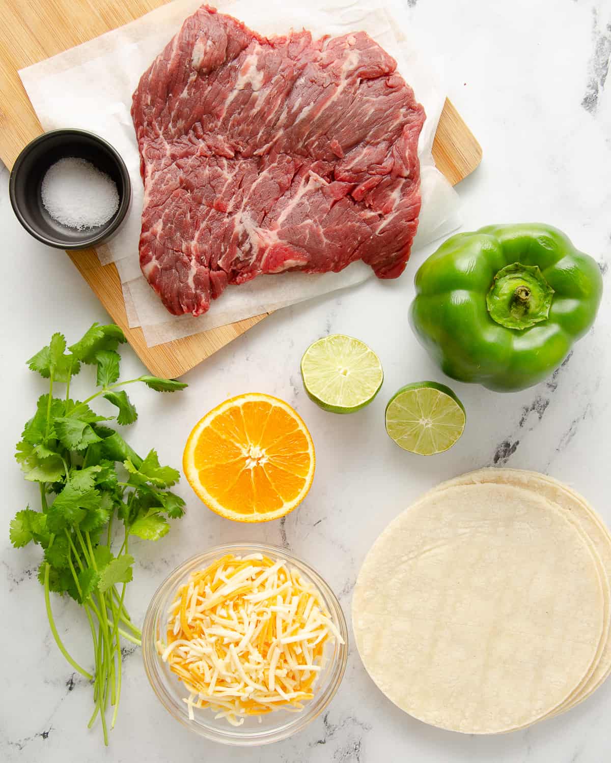 Ingredients to make carne asada quesadillas on a marble countertop.