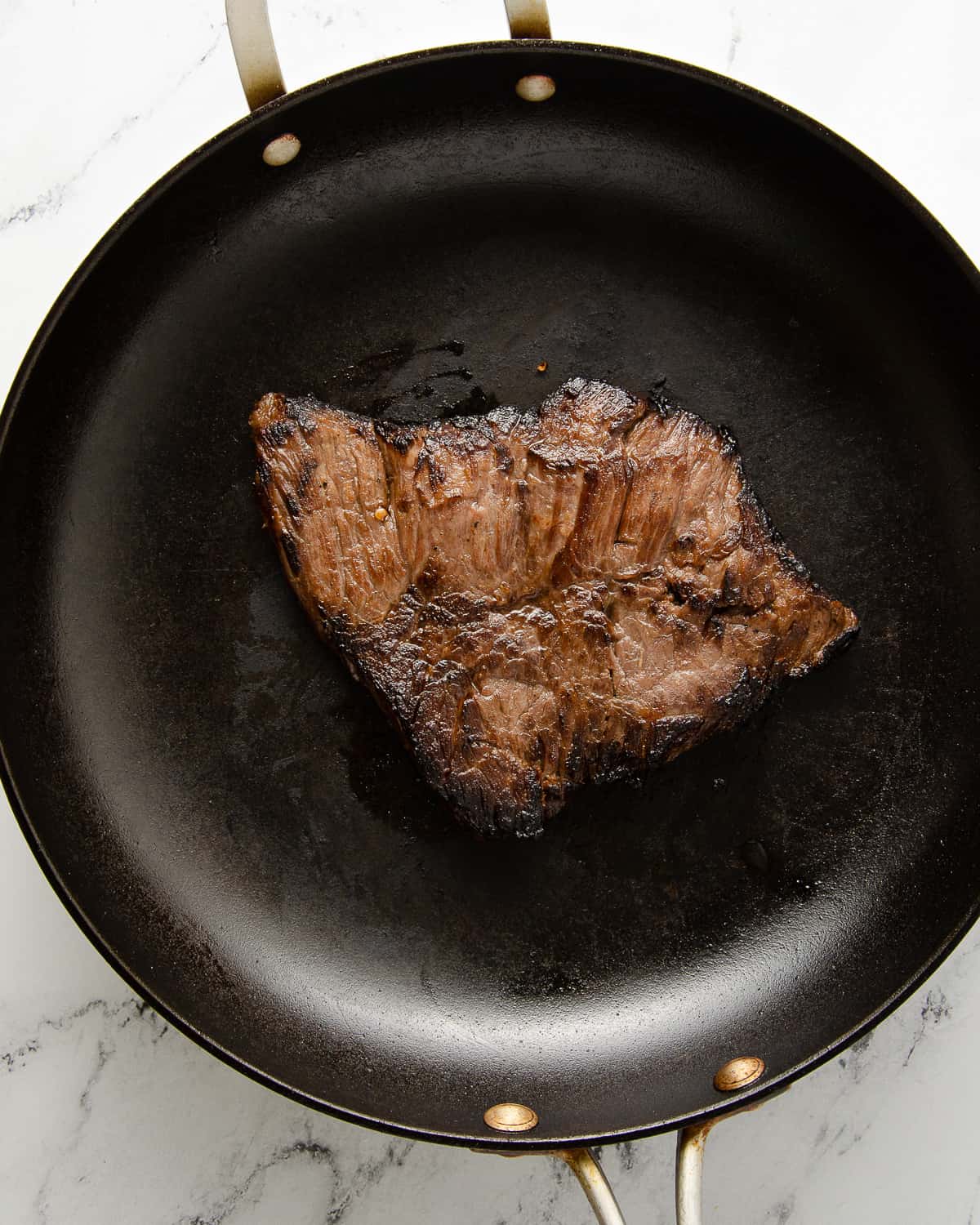 A seared carne asada on a skillet.