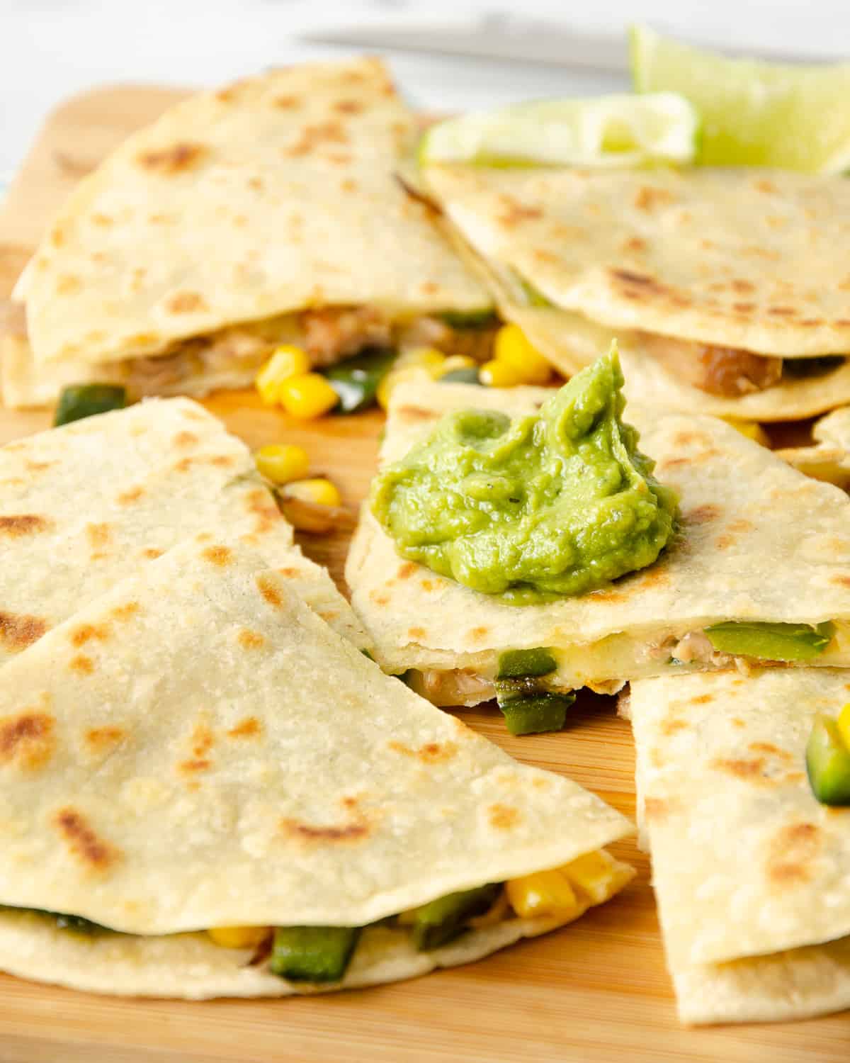A side view of carnitas quesadillas topped with a dollop of guacamole.