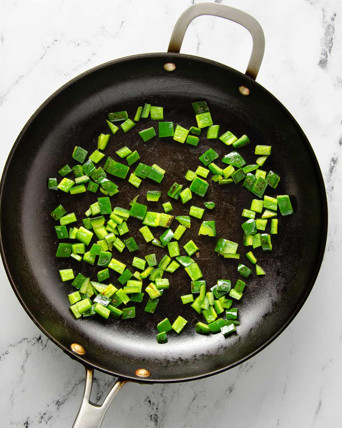 Diced poblano cooked through in a skillet.