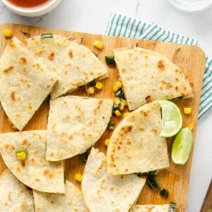 A featured image of a cutting board topped with carnitas quesadillas cut into quarters.