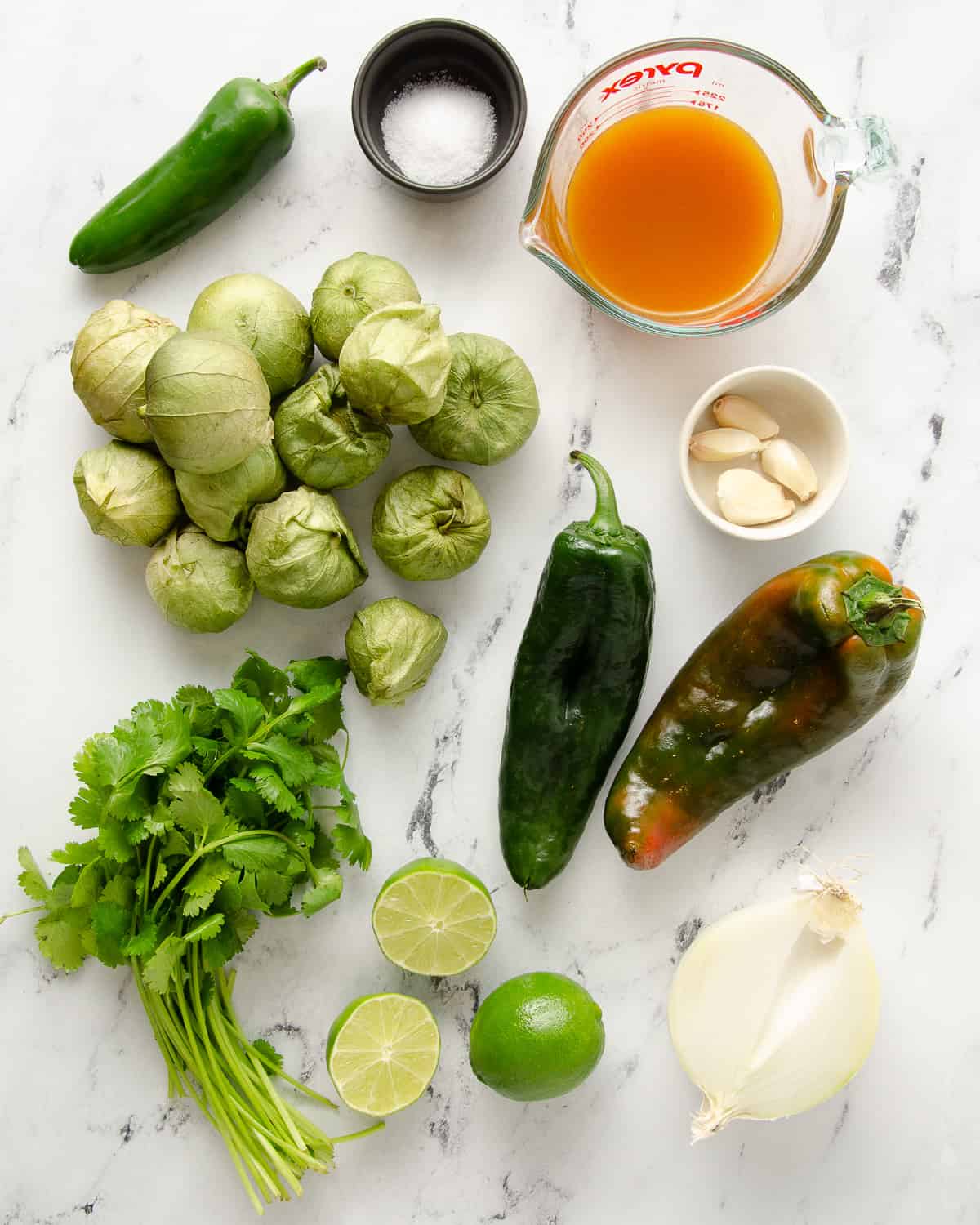 All the ingredients to make green enchilada sauce on a marble countertop.