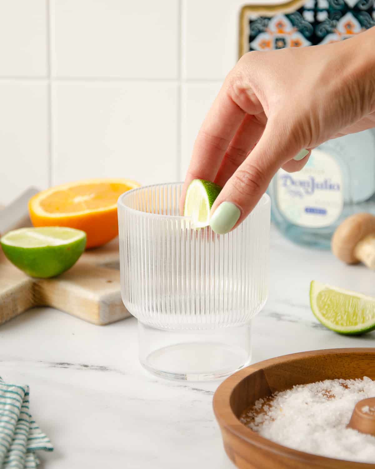 Moving a lime over the rim of a cocktail glass to add a margarita salt rim.
