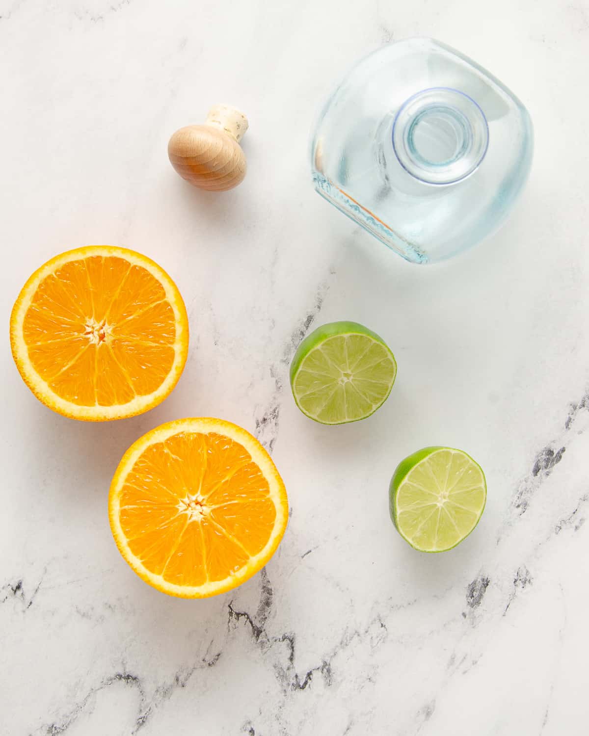 Ingredients needed to make a skinny margarita: tequila bottle, an orange and a lime.