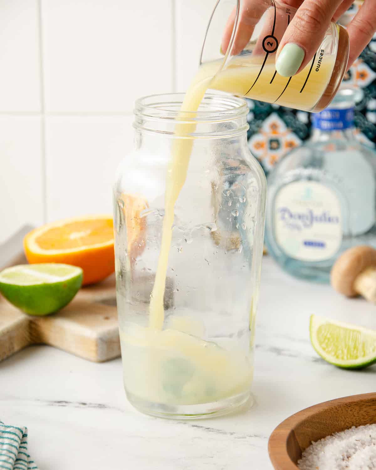 Pouring lime juice into a cocktail shaker.