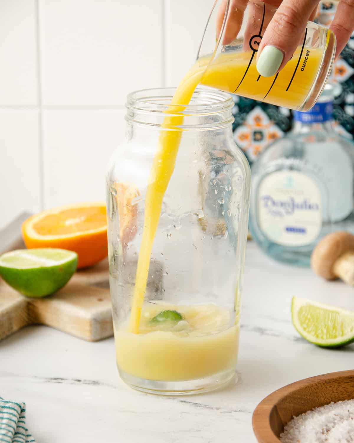 Pouring orange juice into a cocktail shaker.