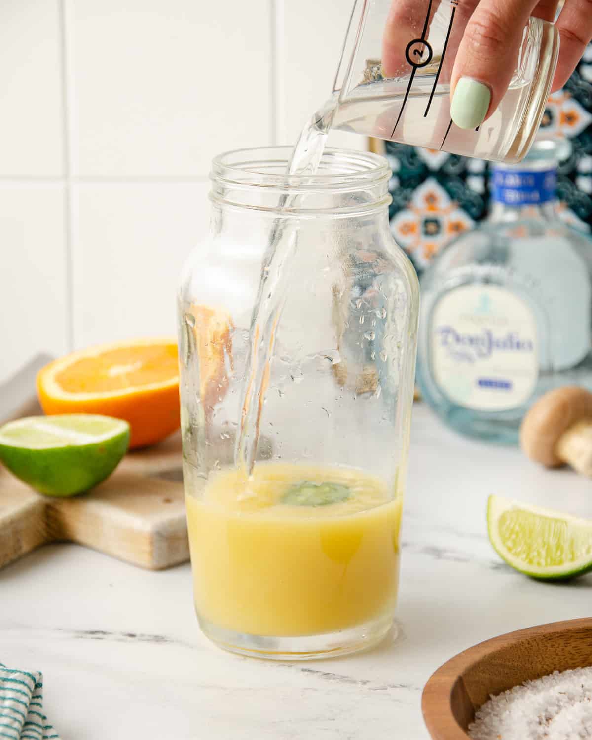 Pouring tequila into a cocktail shaker.