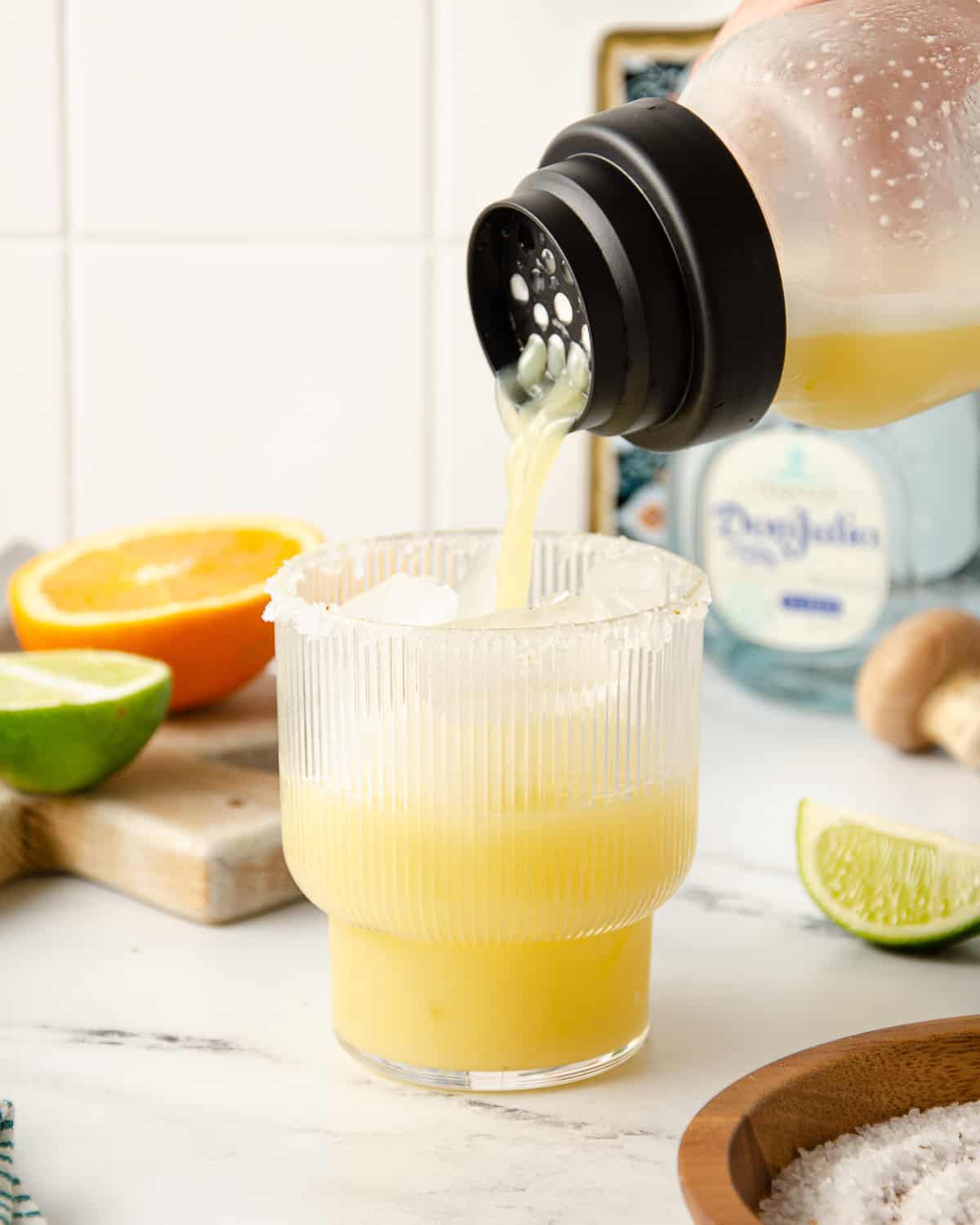 Straining a spicy skinny margarita into a cocktail glass filled with fresh ice.