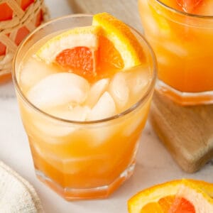 A glass of grapefruit orange juice with orange slices in it.