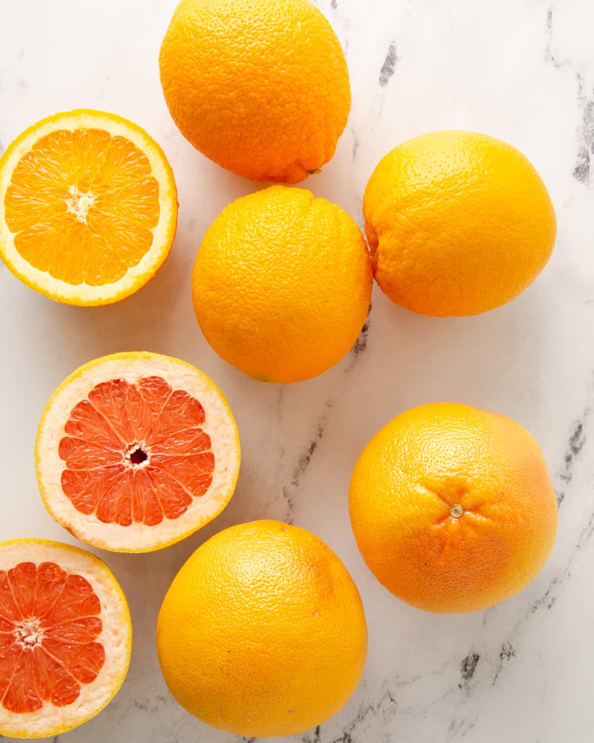 Some whole and some orange halves on a white countertop.