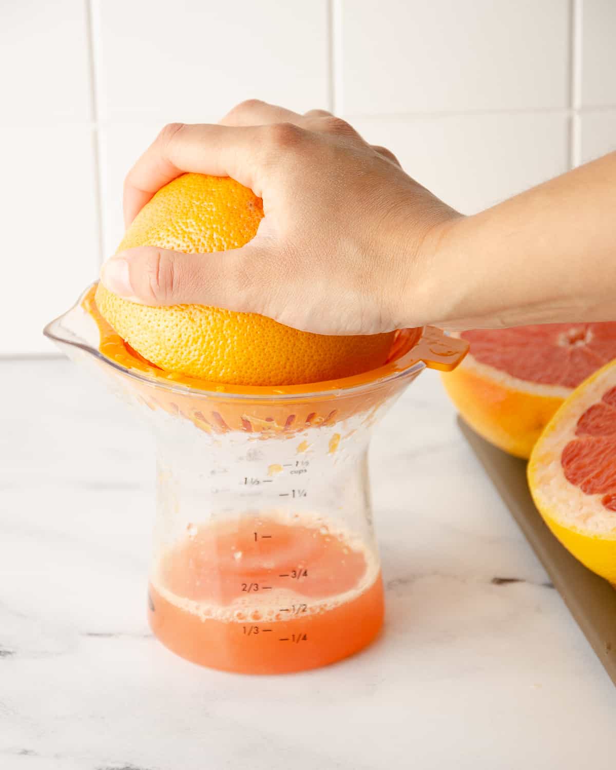 A hand squeezing a grapefruit half on a juicer.