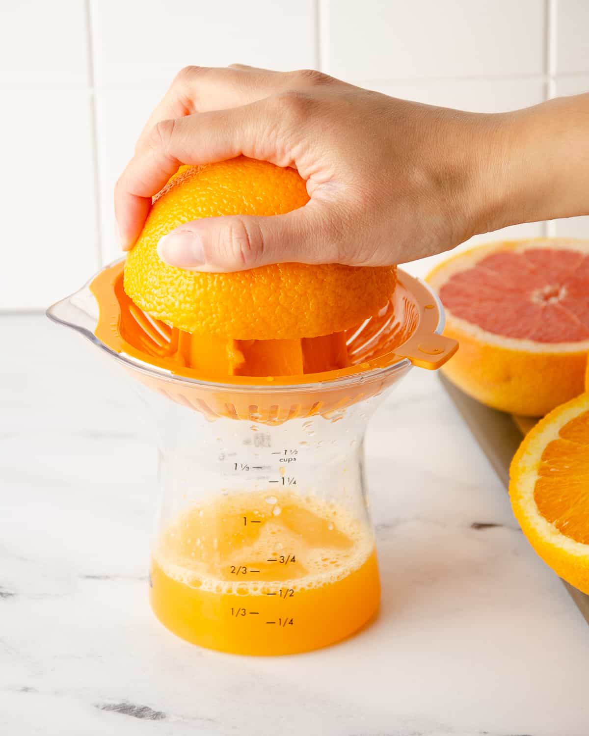 A hand squeezing an orange half on a juicer.