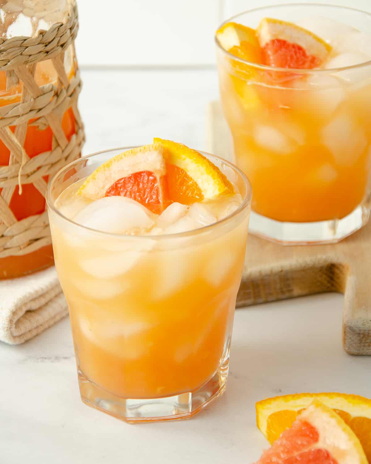 Two glasses of orange and grapefruit juice with orange slices.