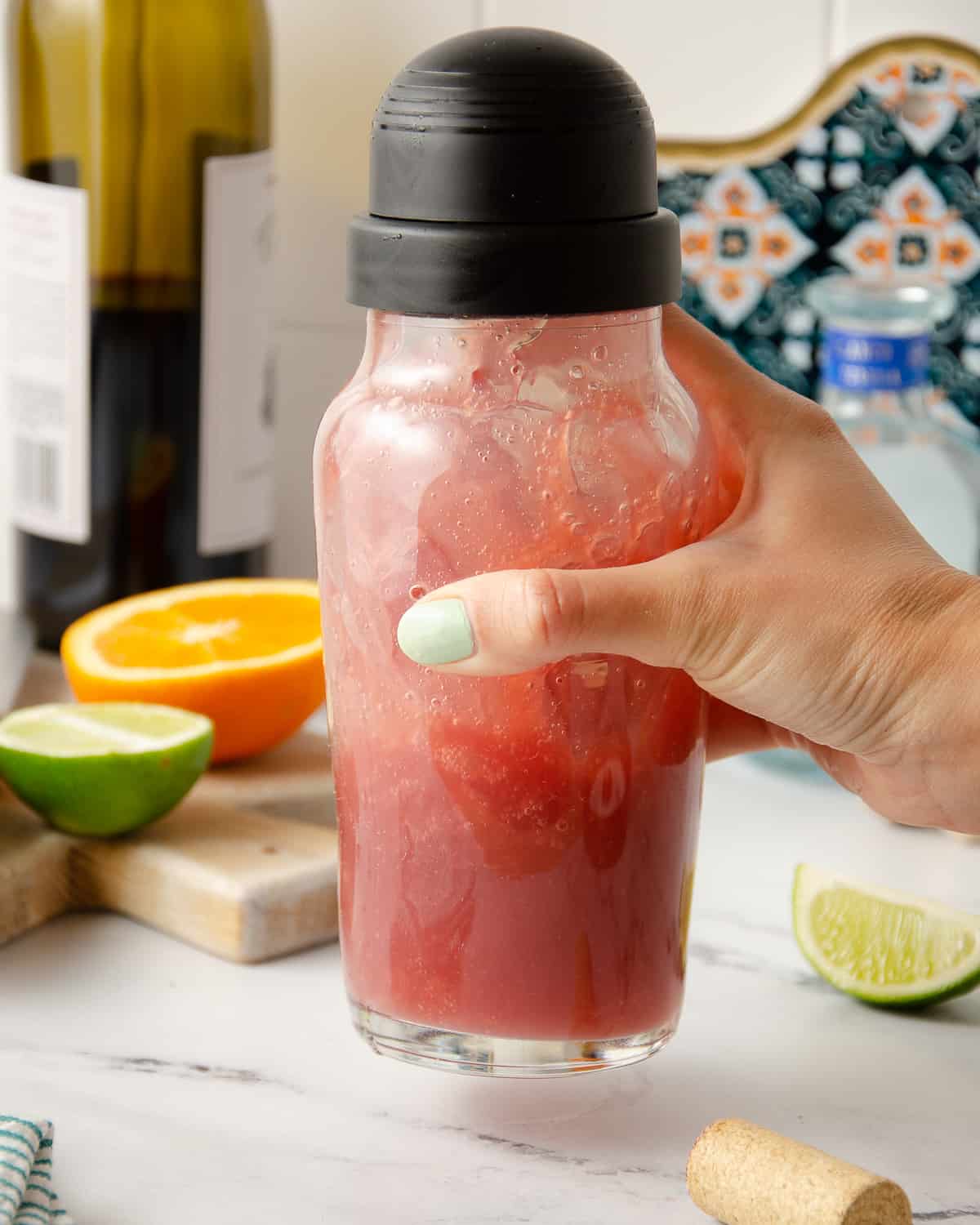 A hand shaking a cocktail shaker of red sangria margarita.