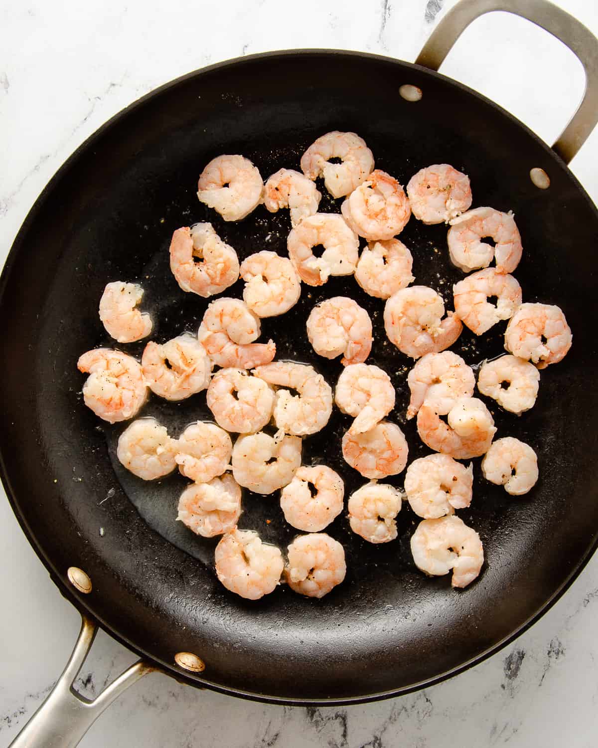A skillet with cook seasoned shrimp for tacos.