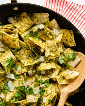 Chilaquiles Verdes in a skillet topped with cilantro and onion.
