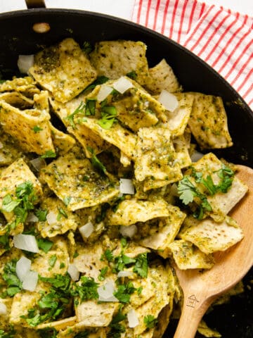 Chilaquiles Verdes in a skillet topped with cilantro and onion.