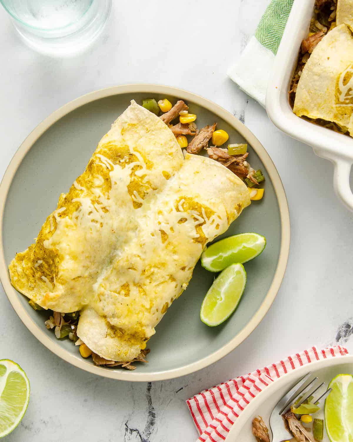 Two enchiladas on a plate topped with cheese.