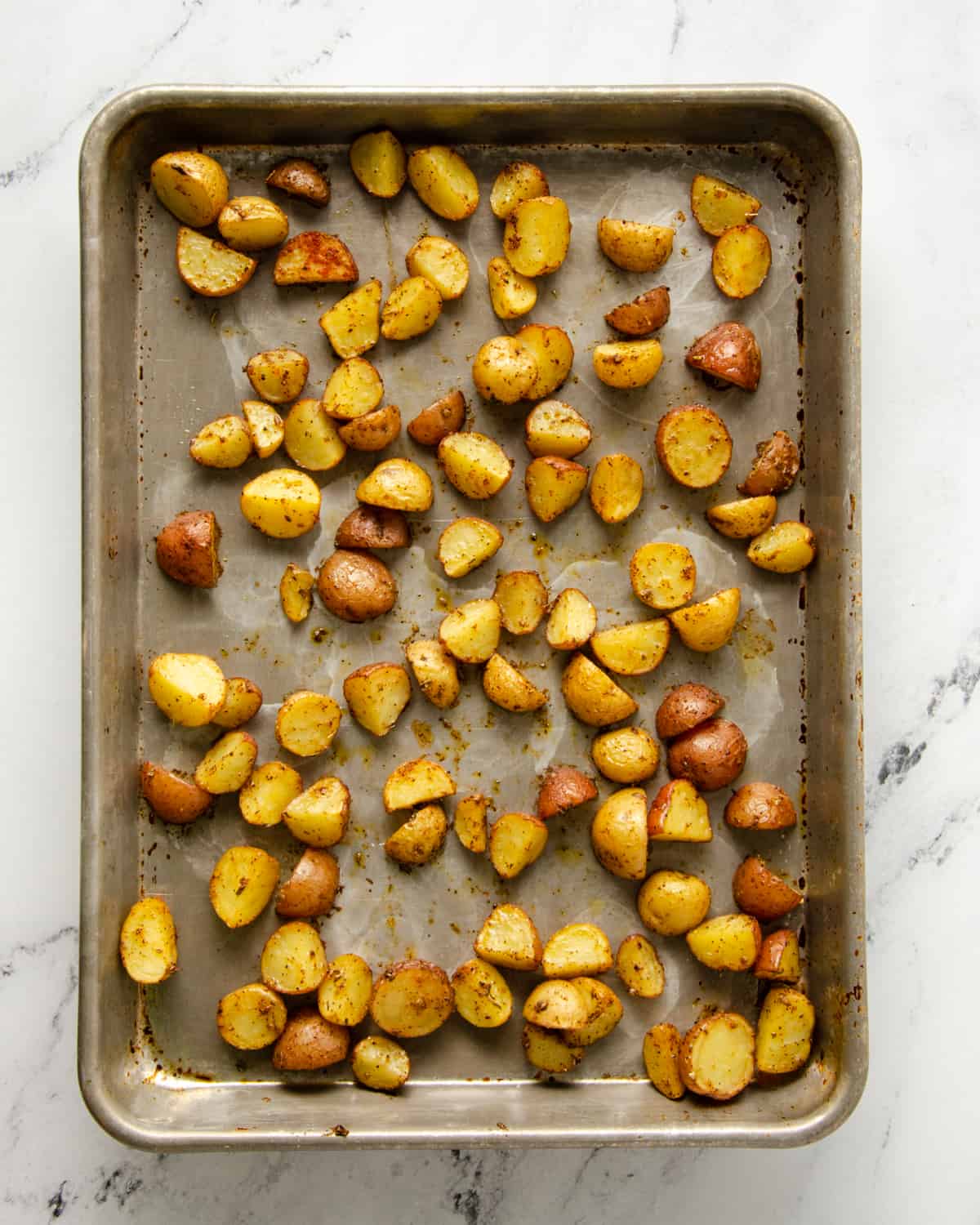 Partially roasted breakfast potatoes on a baking sheet.