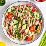 Protein Pasta Salad in a serving bowl topped with creamy lemon mint dressing and fresh mint.