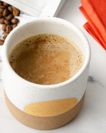 Spanish latte in a mug topped with a sprinkle of cinnamon.