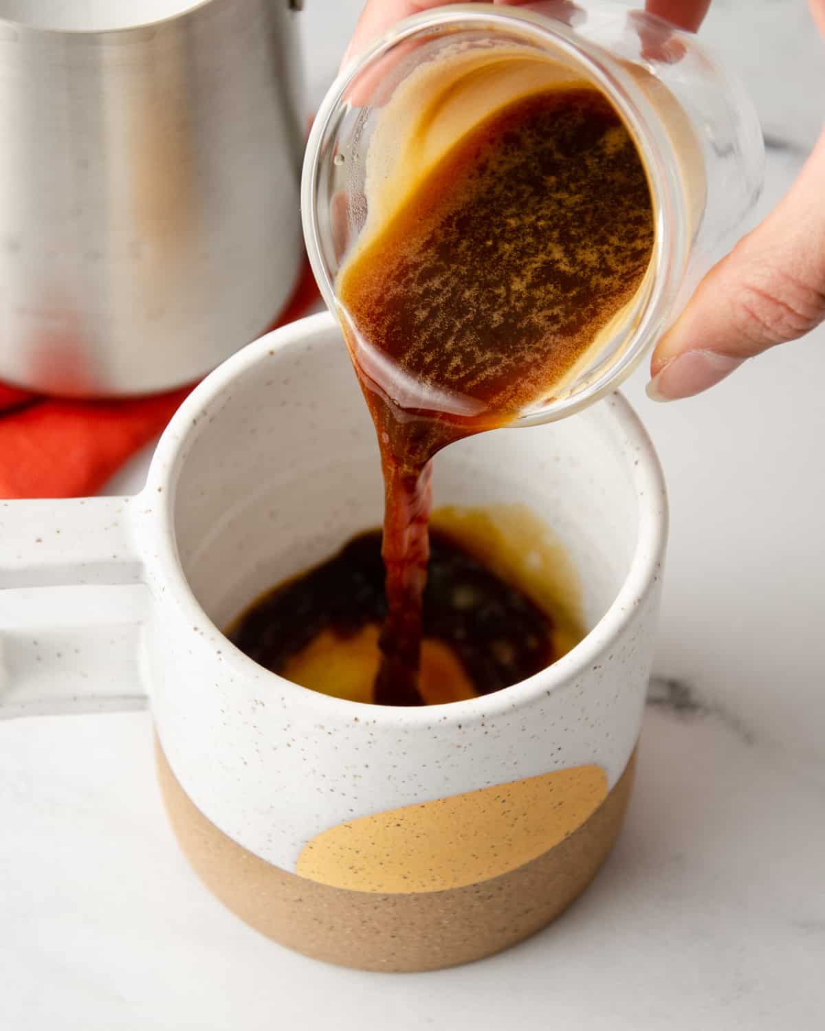 Pouring a shot of espresso into a coffee mug.