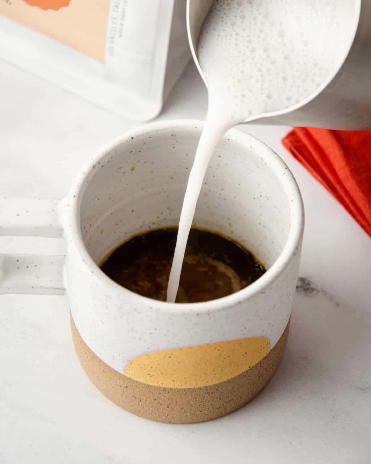 Pouring scalded milk into a shot of espresso.
