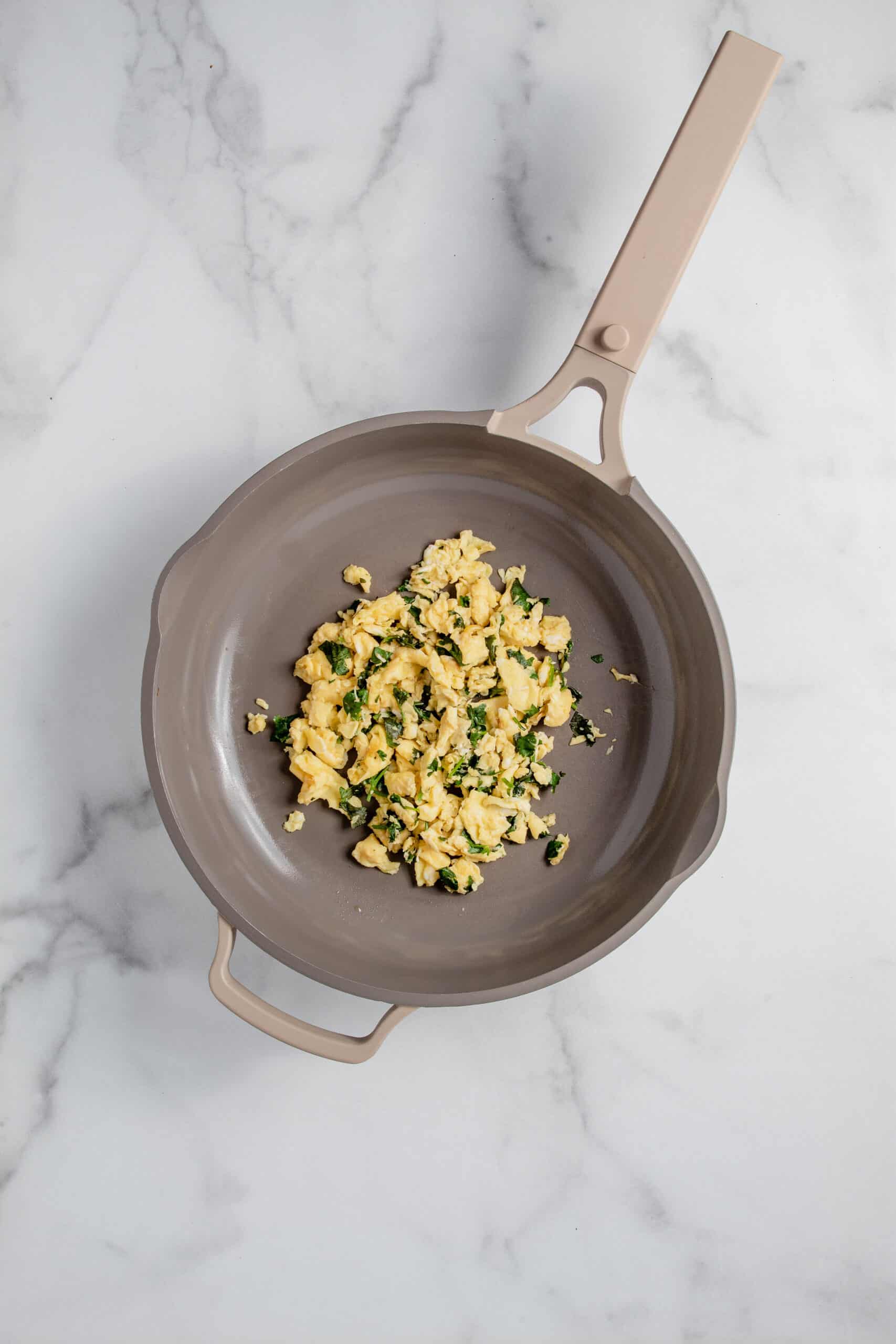 Scrambled eggs with cilantro in a skillet.