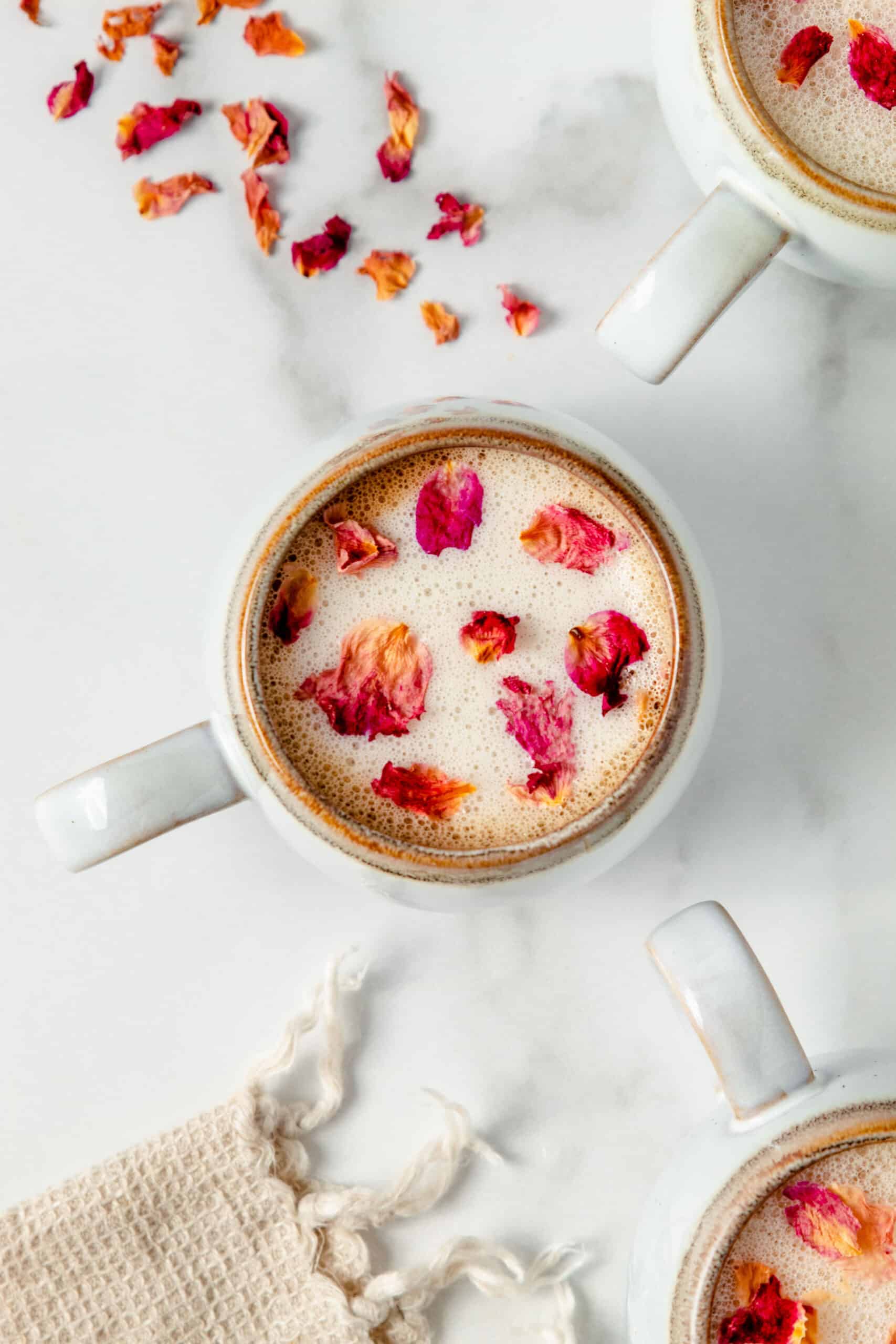Rose latte with rose petals in a white coffee mug.