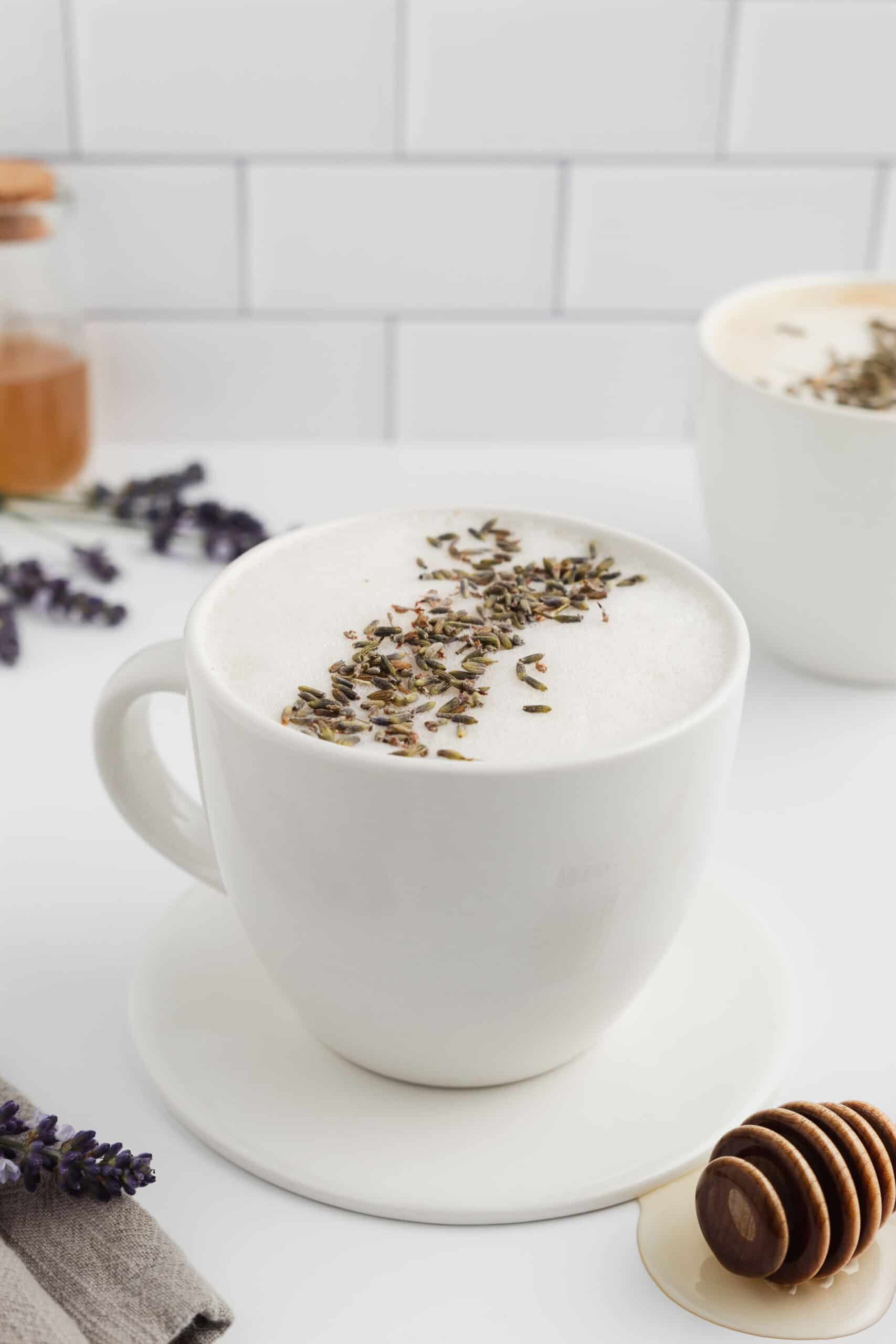 A mug of honey lavender latte topped with foam and lavender.