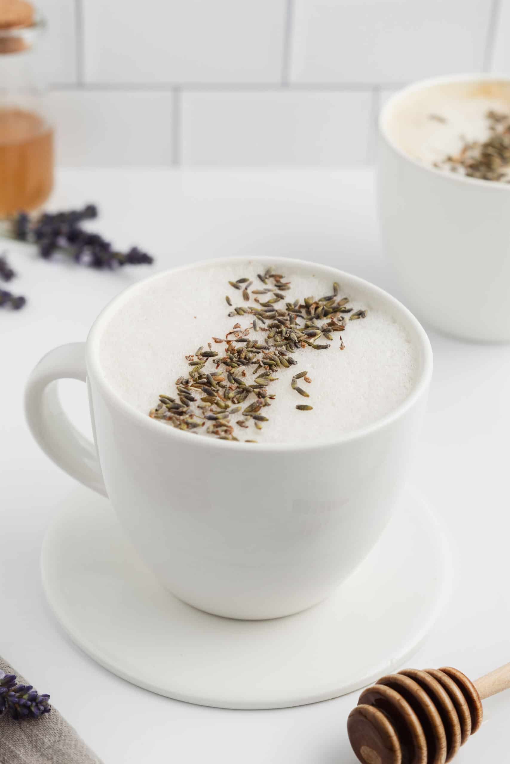 A mug of honey lavender latte topped with foam and lavender.