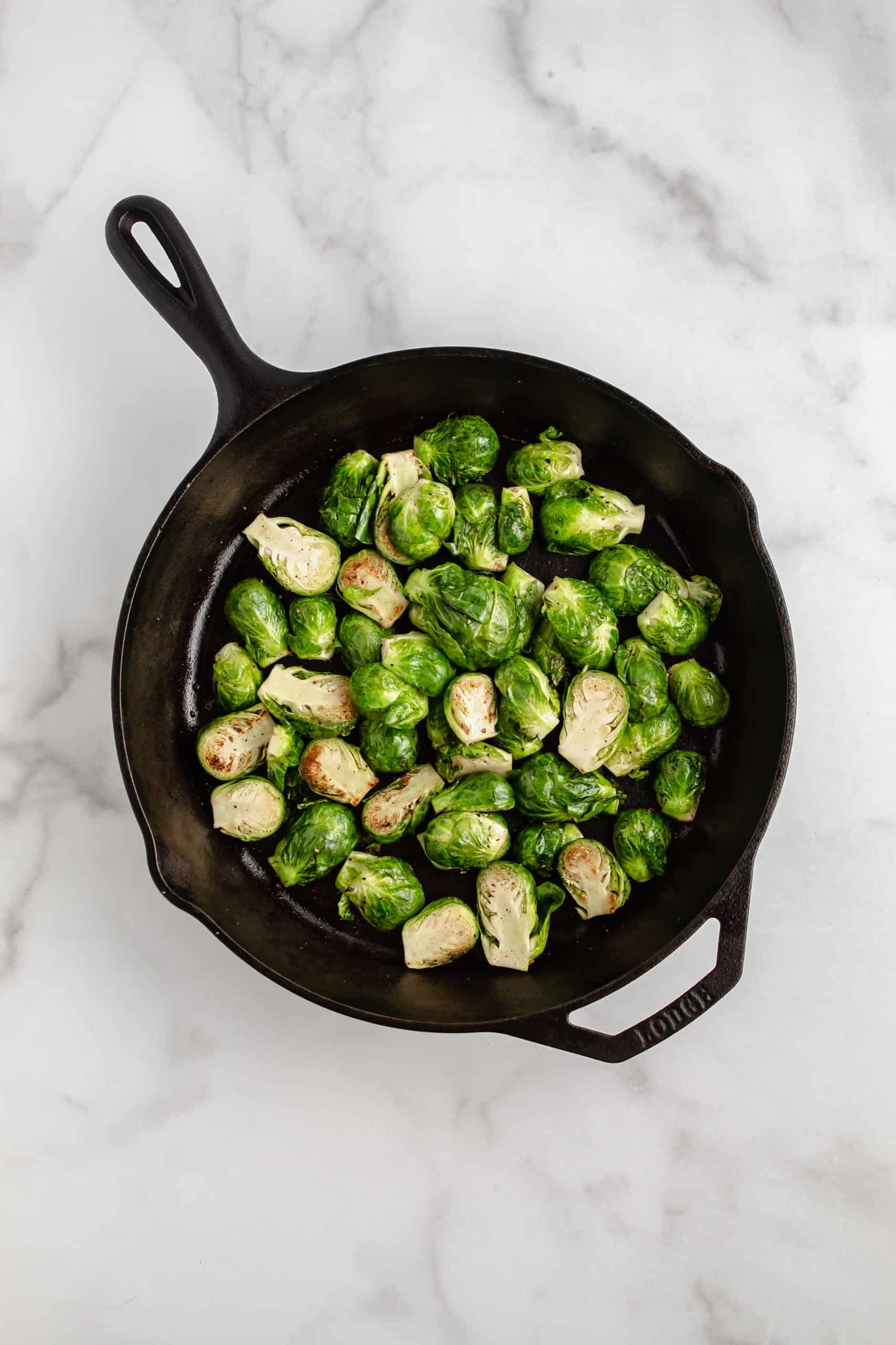A cast iron skillet with browned Brussels sprouts.