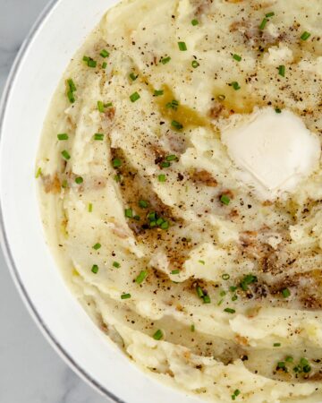 Featured image of A bowl of mashed potatoes topped with salt, pepper, butter, and chives.