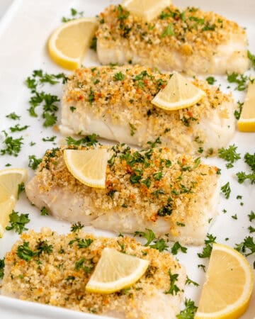 Panko crusted baked cod topped with parsley and lemon wedges.
