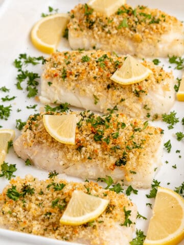 Panko crusted baked cod topped with parsley and lemon wedges.