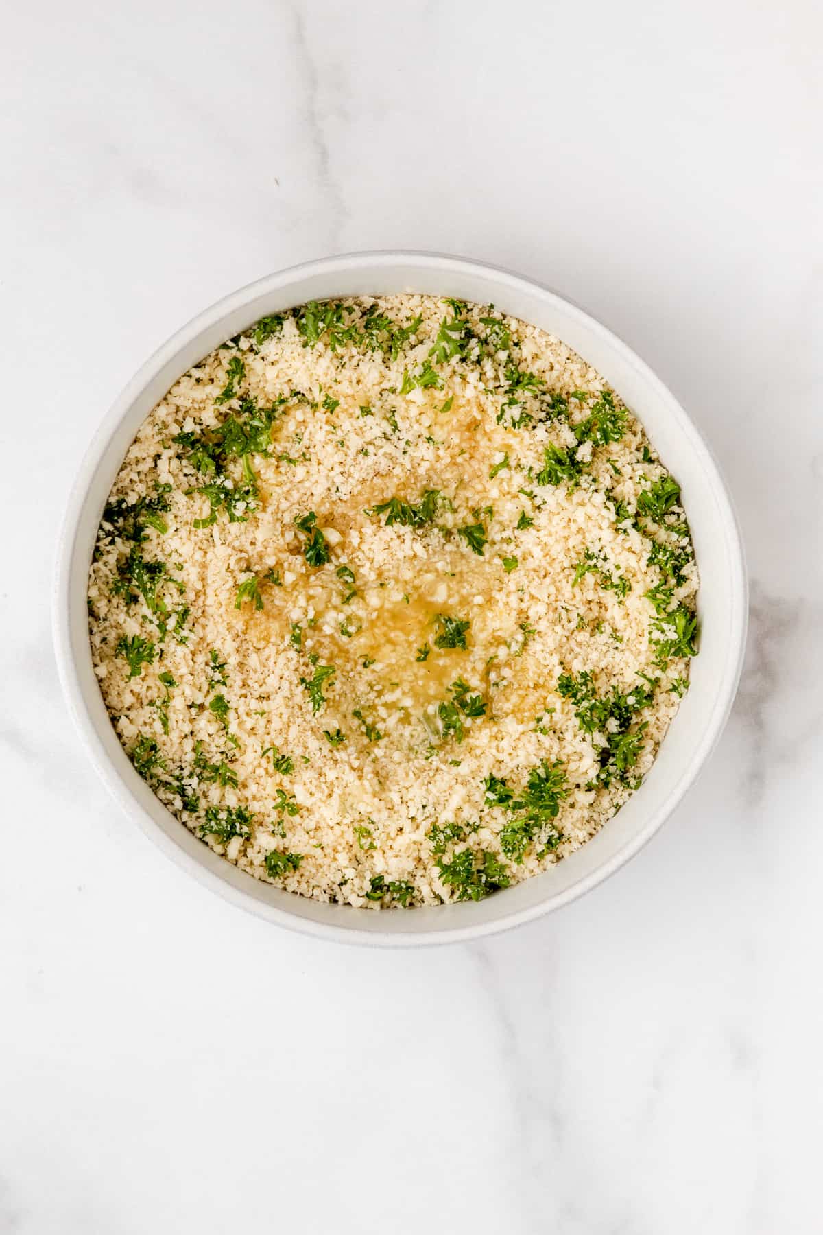 Panko breadcrumbs with butter and parsley in a mixing bowl.