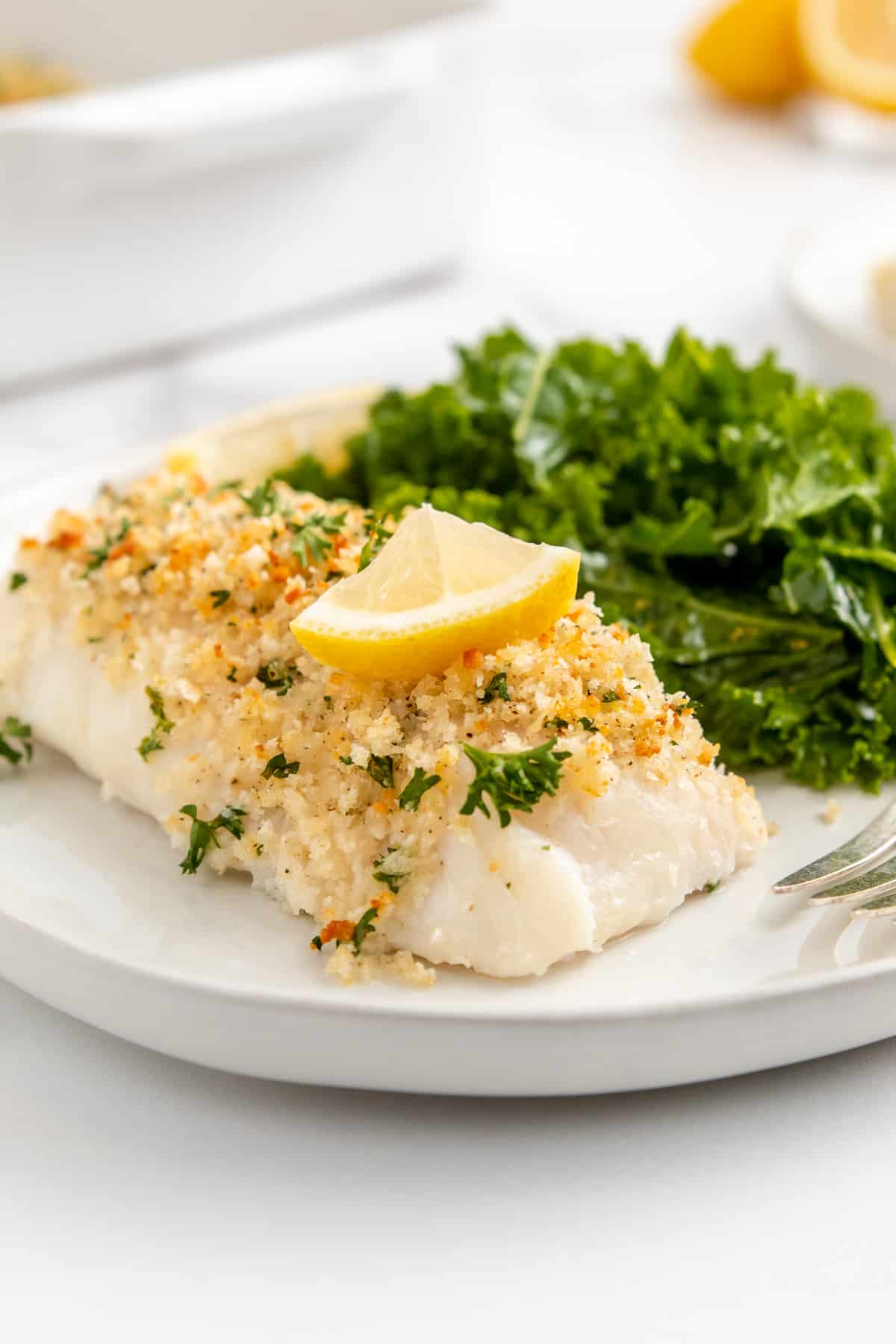 A piece of panko coated baked cod plated with sautéed kale.