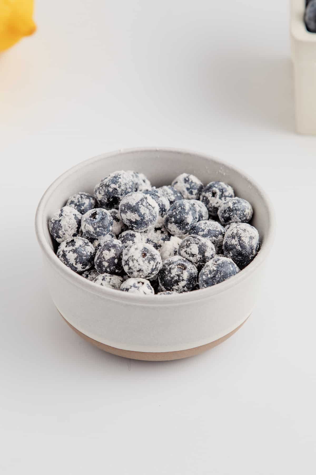 Blueberries in a bowl tossed with flour.