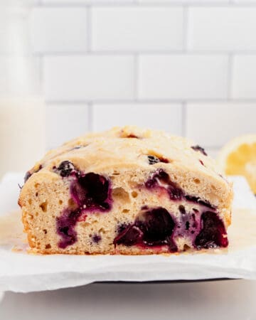 A loaf of gluten free lemon blueberry bread with a slice missing.