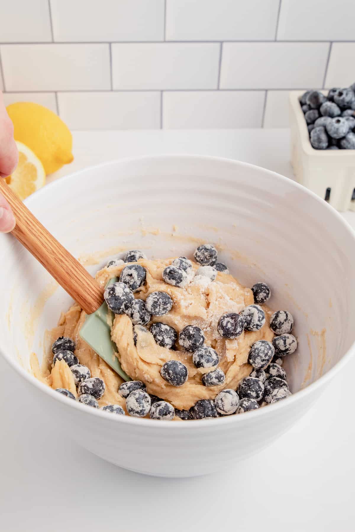 Loaf batter being mixed with fresh blueberries in a mixing bowl.