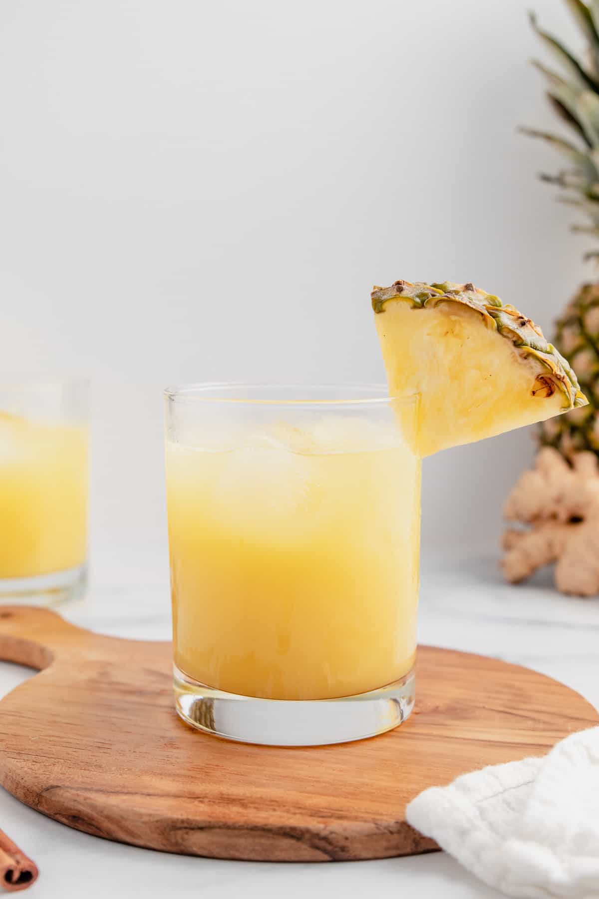 A glass of pineapple ginger juice topped with a pineapple slice.