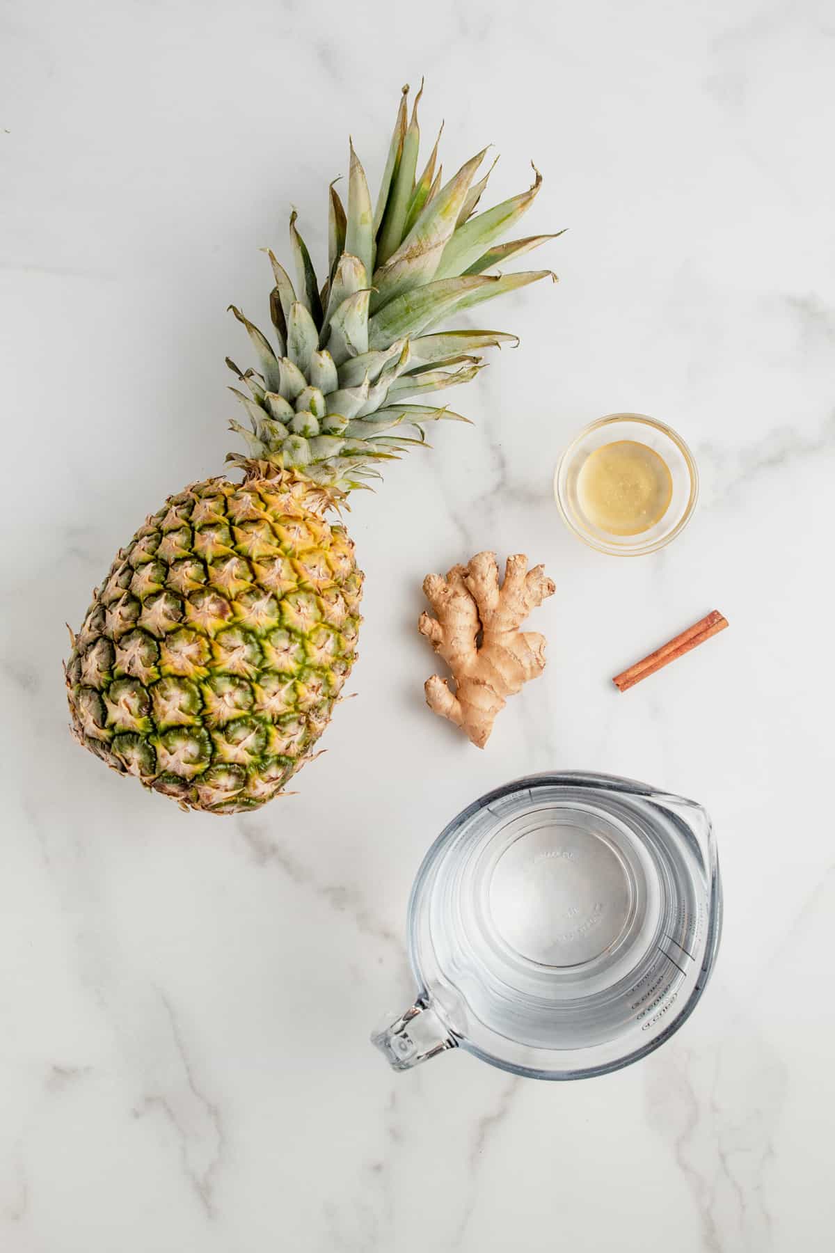 Ingredients needed to make pineapple ginger juice: pineapple, ginger, cinnamon, honey, and water.