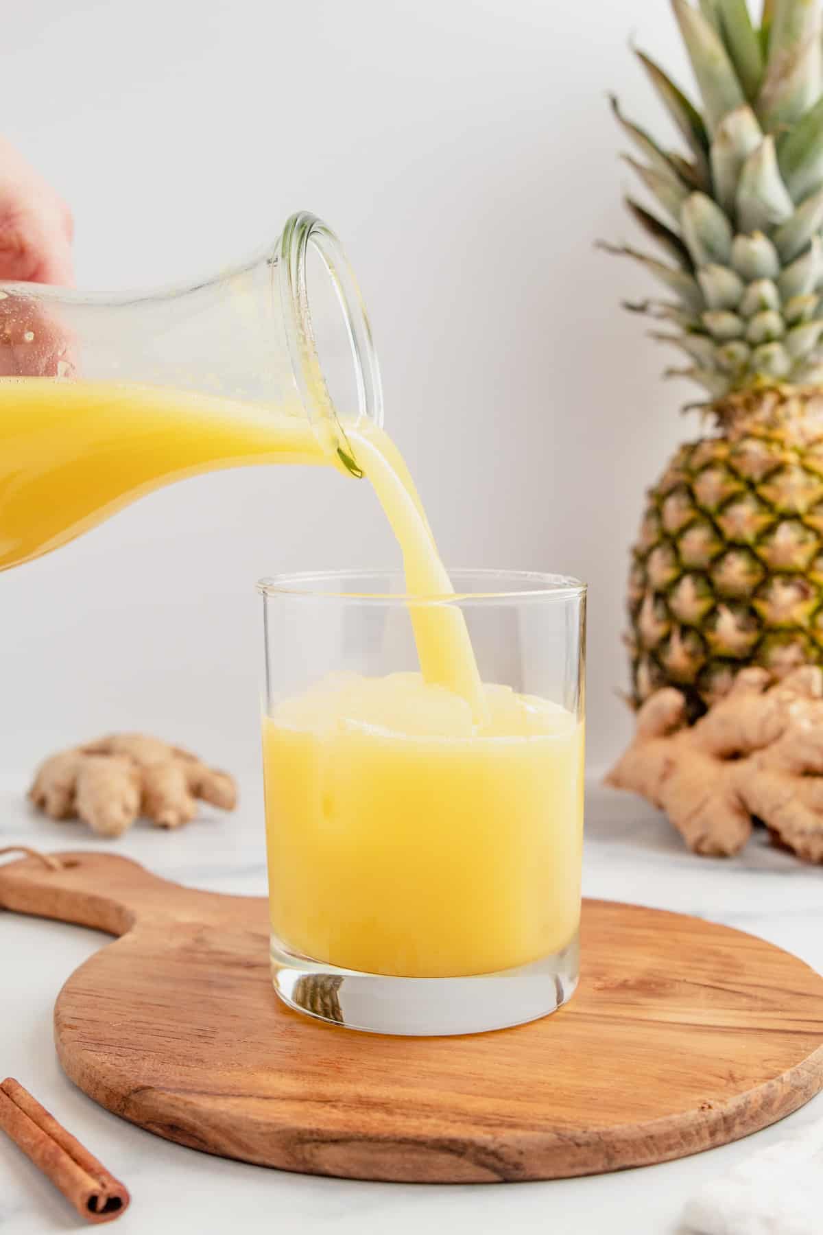 Pouring ginger pineapple juice into a glass.