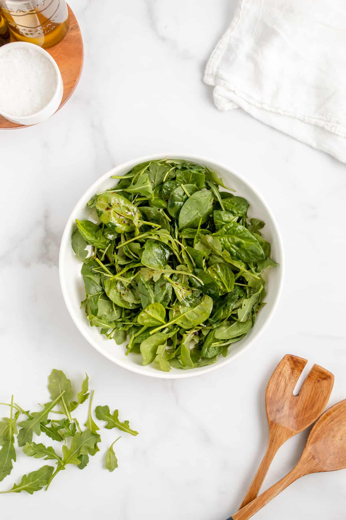 Spinach and arugula salad with balsamic vinaigrette in a white serving bowl.