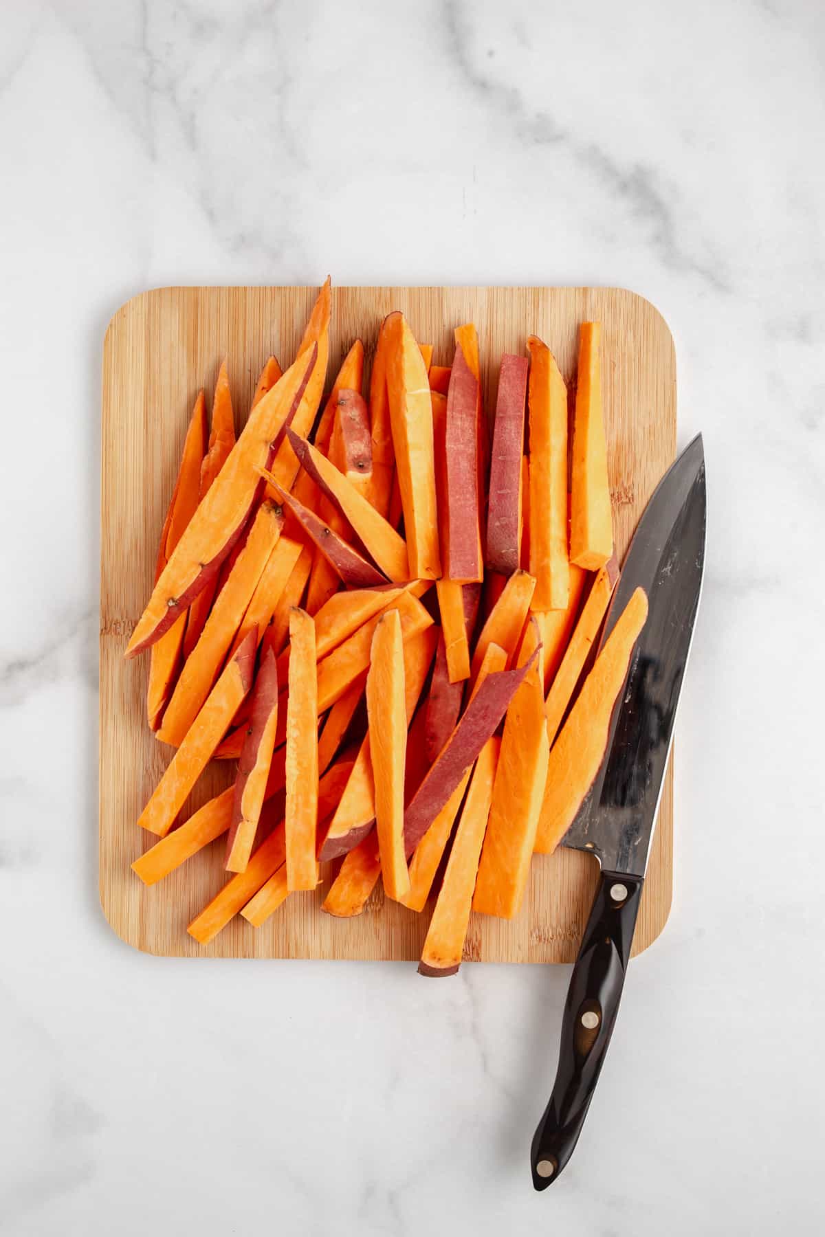 Sliced sweet potato fries on a cutting board.
