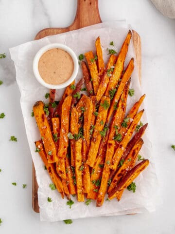 Baked sweet potato fries topped with salt and fresh herbs.