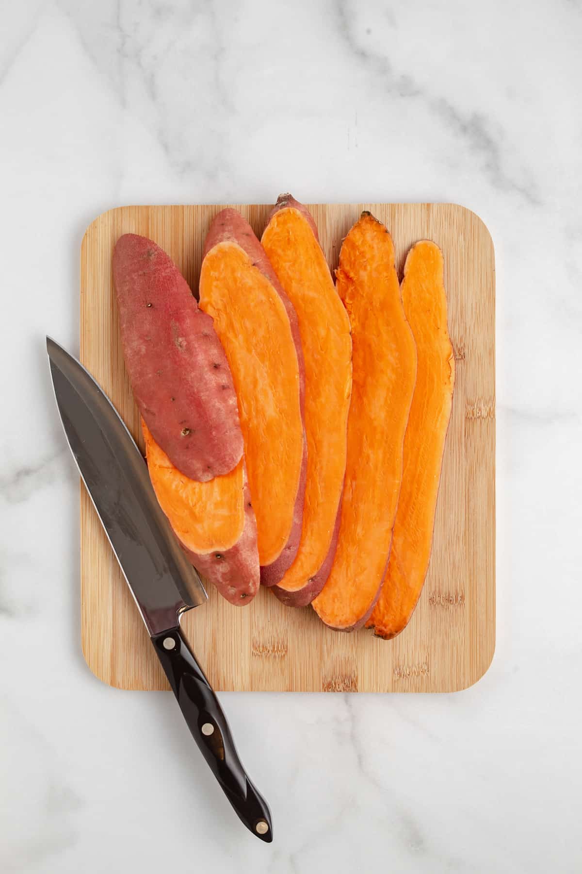 A sweet potato cut into slabs on a cutting board.