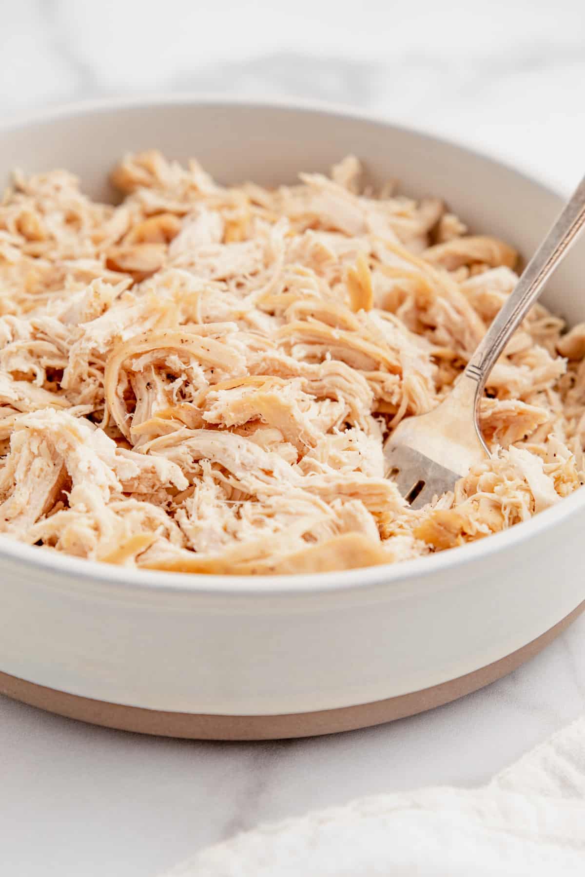 Pulled chicken in a bowl with a fork.