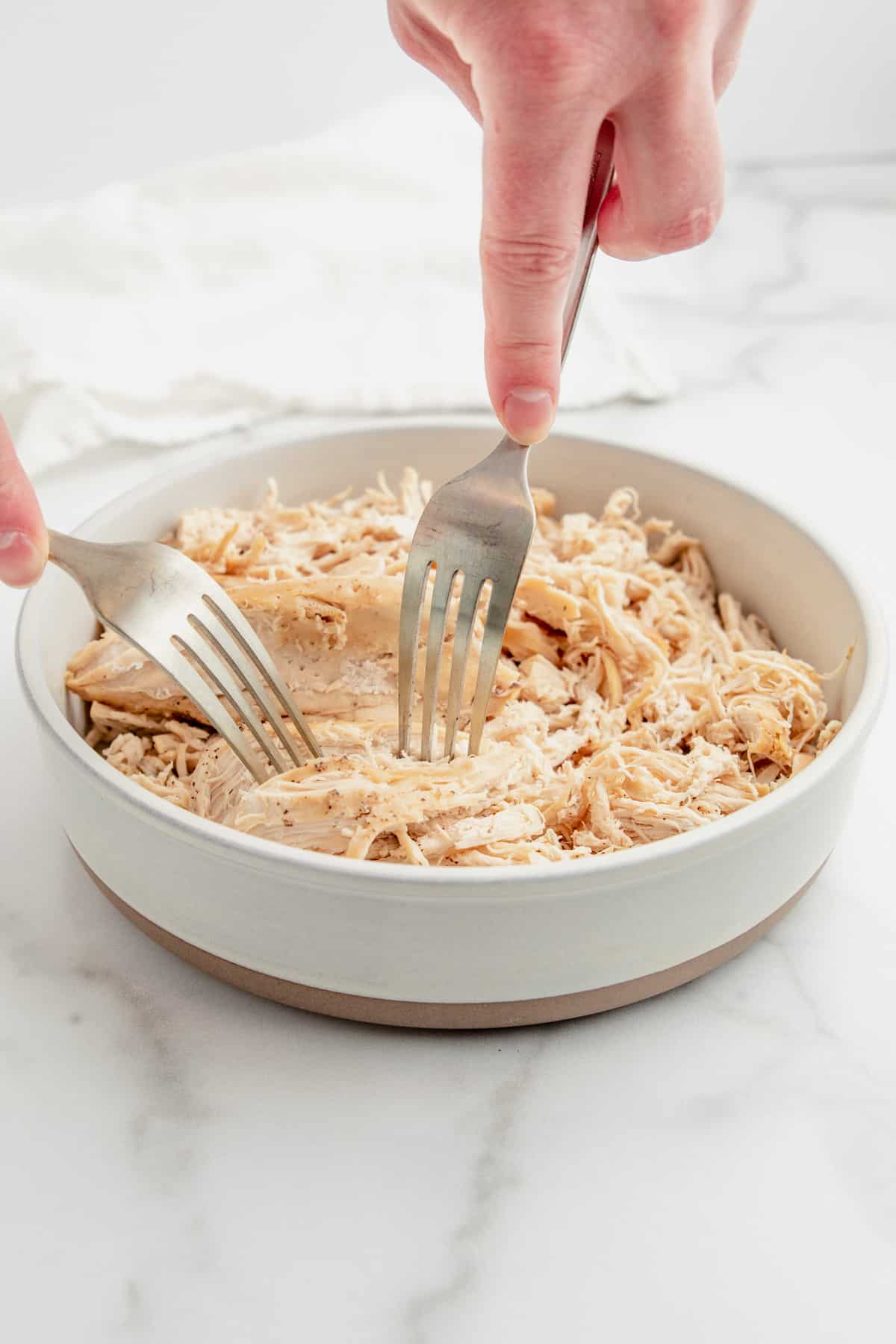 Shredding chicken breasts with two forks.