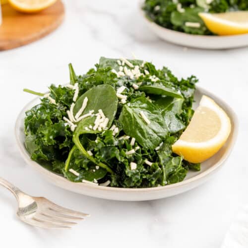 Kale and spinach salad in a bowl topped with a lemon vinaigrette.